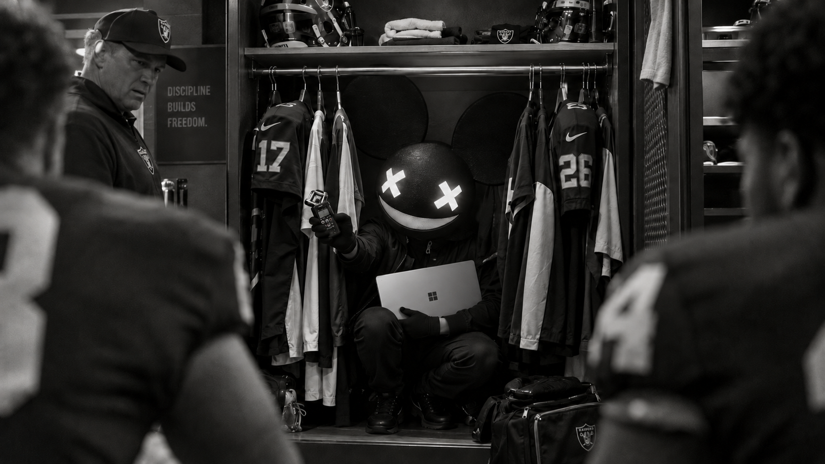 Concept: deadmau5 hides among jerseys with his Windows laptop and recorder.